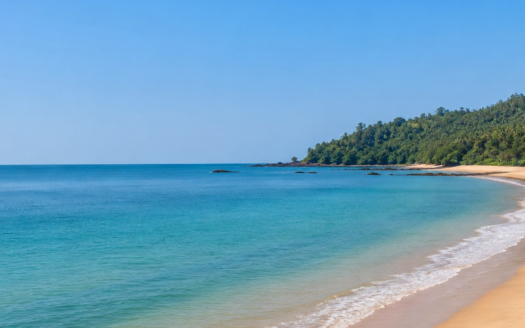 Scenic coastal landscape of Vengurla beach in Sindhudurg, Maharashtra, showing blue sea, sandy shoreline and lush green hills.